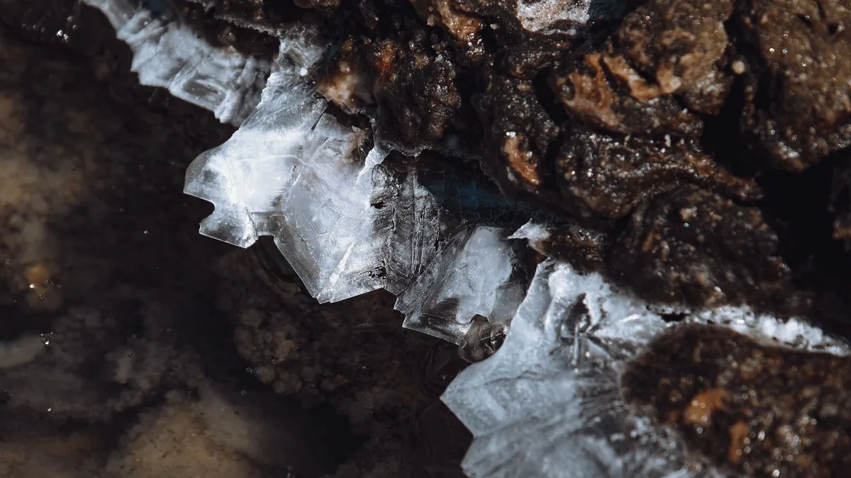 Detailed view of ice crystals forming on rough rocky surface during winter.